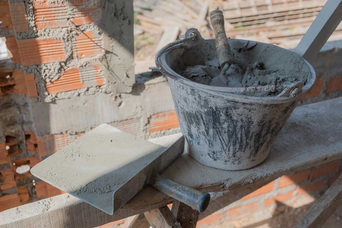 نمایی از سطل ملات ساختمانی و ابزار بنایی در فضای واقعی کارگاهی، در پایان عملیات اجرا