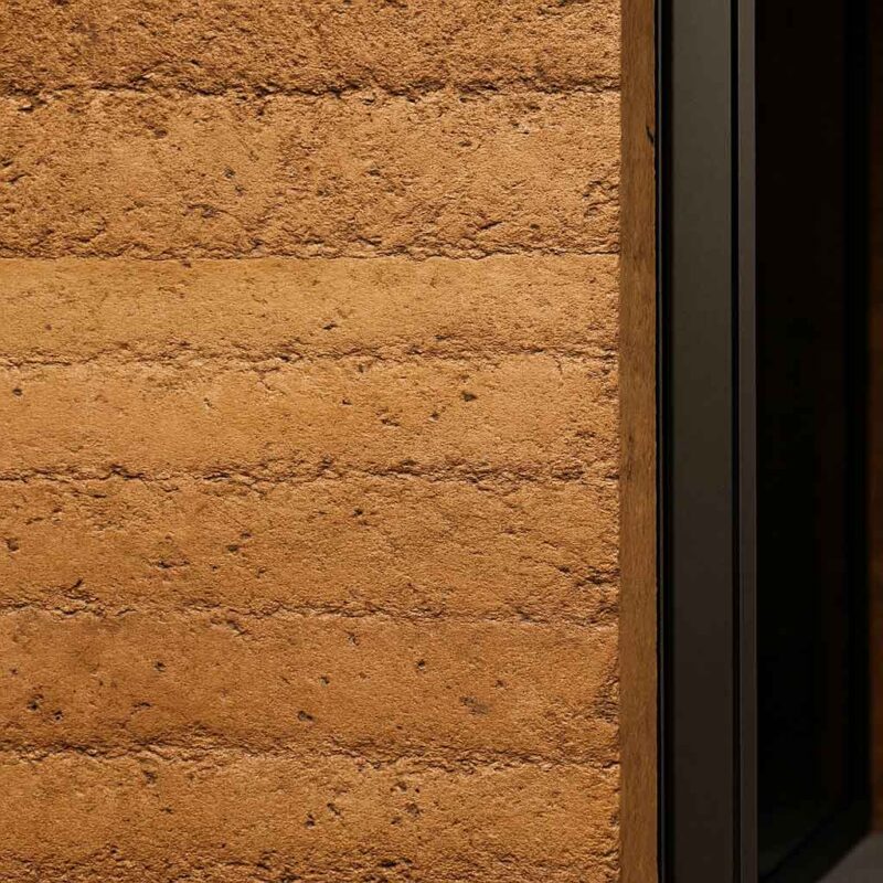 نمای نزدیک از دیوار ساخته&zwnj;شده با خاک رس فشرده، نشان&zwnj;دهنده بافت و لایه&zwnj;بندی طبیعی مصالح خاکی